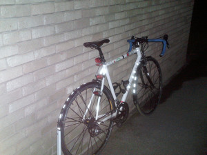 A white bike with reflective lights and stickers on the wheels and frame